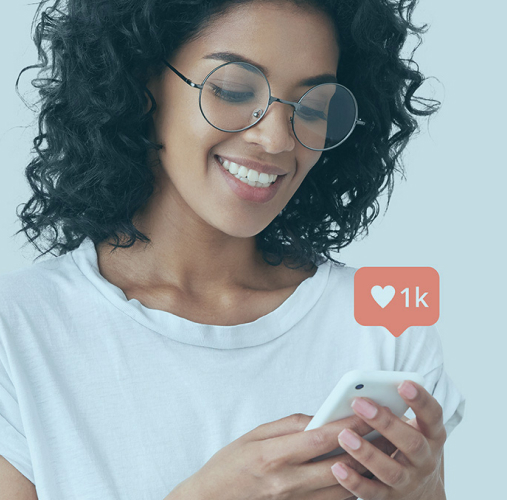 A brunette woman with curly hair and glasses smiles after buying Instagram likes from 1394TA.