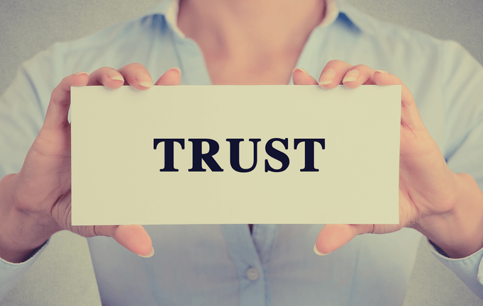 a women holds a cart in her hands that it wrote trust on it